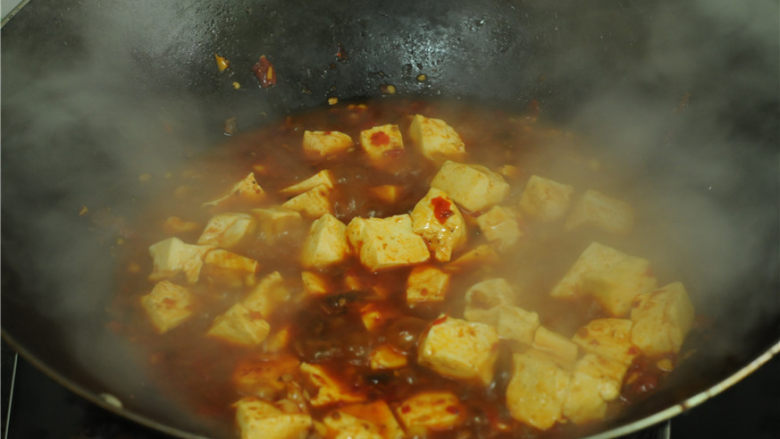 红烧豆腐,烧开后放入豆腐、大火烧煮一分钟,为了避免糊锅,中间适度旋转锅身,取一半水淀粉勾芡,继续旋动锅身烧煮大约一分钟,再放剩下的水淀粉,
