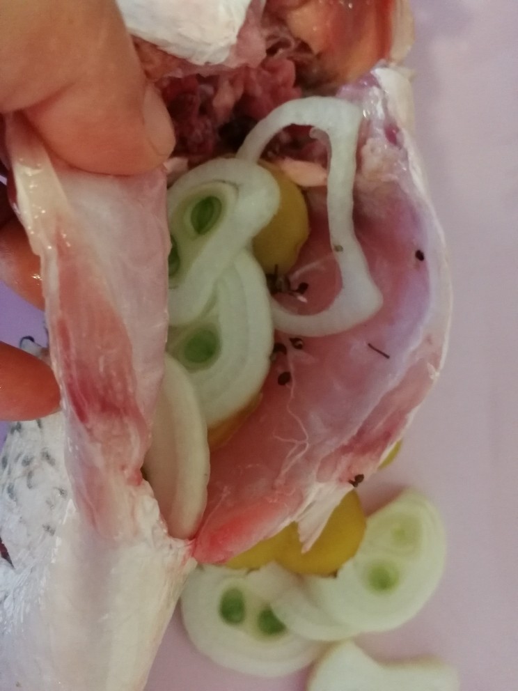年夜菜_麻辣清蒸江鲫鱼&一锅两吃,把葱,姜,花椒粒分别塞进两个鱼肚子里(如图)。