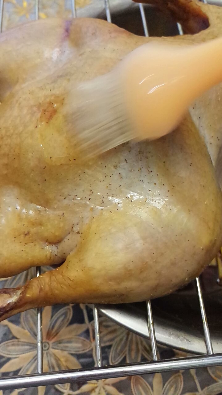 家庭自制烤鸭,将鸭子取出来,再刷一层蜜水。翻个面儿再次放入烤箱中,继续烤半小时