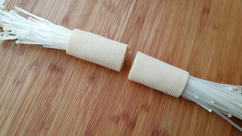 【豆皮金针菇卷】,将豆皮卷起,卷向另一端,要卷紧,用刀在豆皮卷中间切开,一分为二