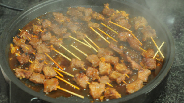 秘制牛肉串,肉串熟透后,将剩下的烤肉酱刷在上面,小火再煎一会儿