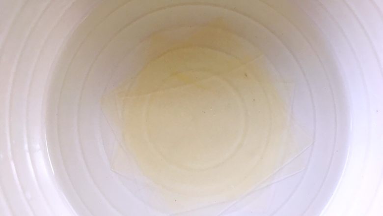 三色堇鲜花慕斯蛋糕(6寸),慕斯糊冷藏凝固后,再来做镜面层,取一片吉利丁片用冷水泡软