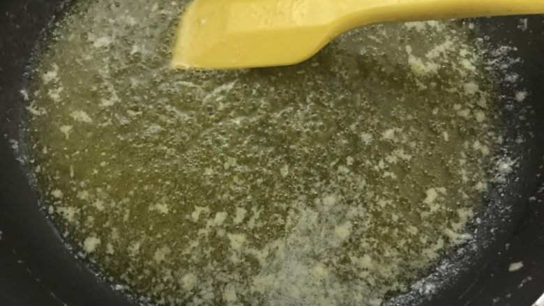 手工牛轧饼,取不粘锅,把黄油倒入,小火加热到冒小泡。