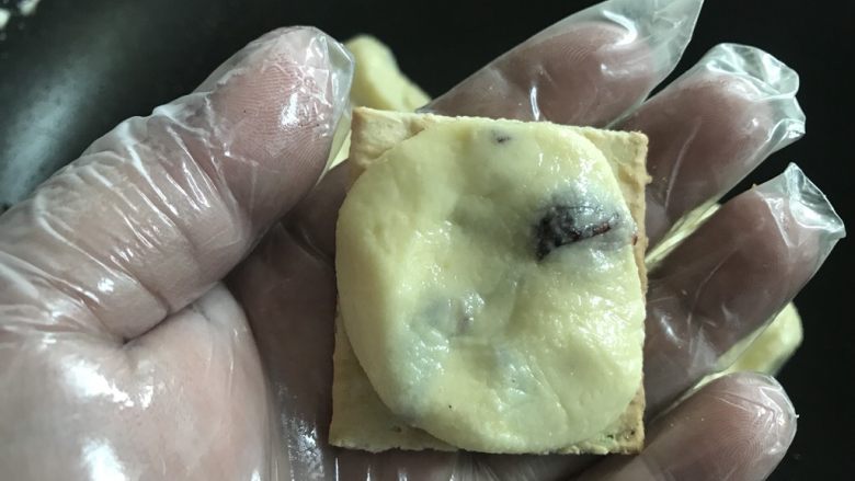 手工牛轧饼,取大概8克的牛轧糖,整圆,按平。贴在一块饼干上。