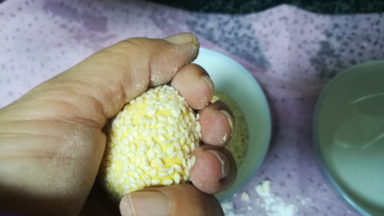 简单易学还喷喷香的南瓜麻饼,把手指并拢,轻轻往掌心用力,如图,让芝麻陷入面团,以防等下脱落。