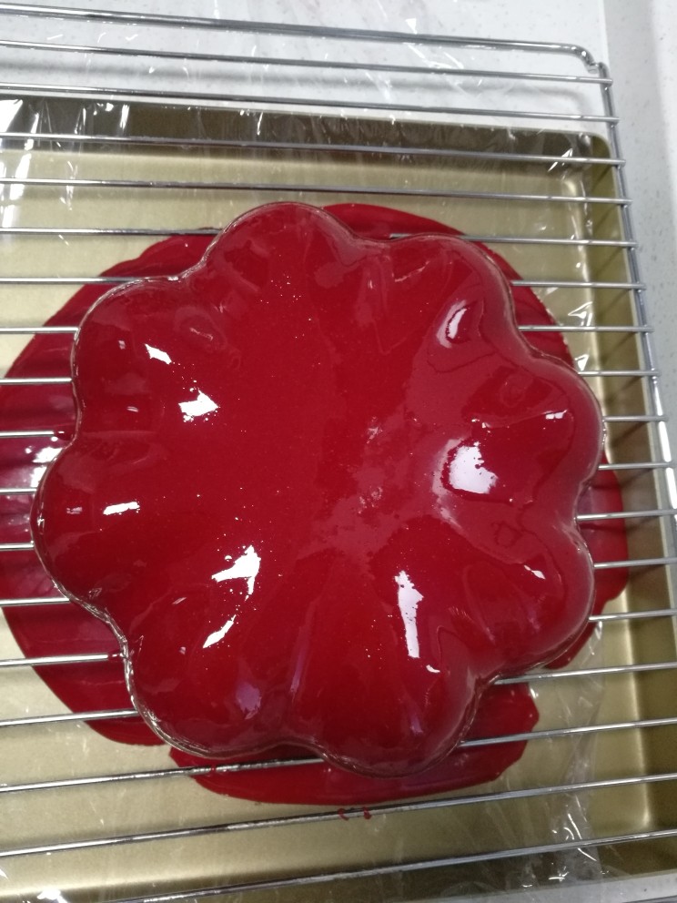 情人节必备巧克力淋面慕斯,第二天取出巧克力淋面,隔水回温,同时搅拌约一分钟,这里面温度为30℃~35℃,此时淋面将呈光亮流淌状态。然后取出做好的慕斯,将淋面淋在慕斯上