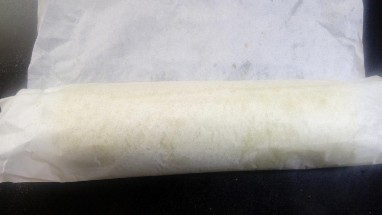 菠菜卷卷(后蛋法),烘烤结束以后,端起烤盘,在台面上轻震几次,震出内部的热气。根据要卷的方式置晾架加上晾至微温,想要正卷的话就正面朝上,反卷就底面朝上,有微微的温度是就可以卷了,不要等到完全晾凉后再卷,那样容易裂开。借助油纸卷起后,定型半小时。