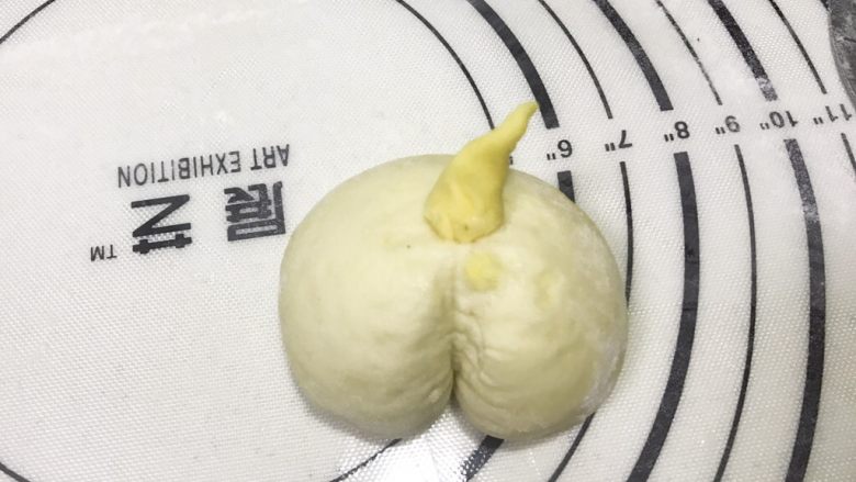 旺财柴犬枣泥包,刷清水粘在面团中央,再用刮板在面团中间压一道小口,做成屁股状;