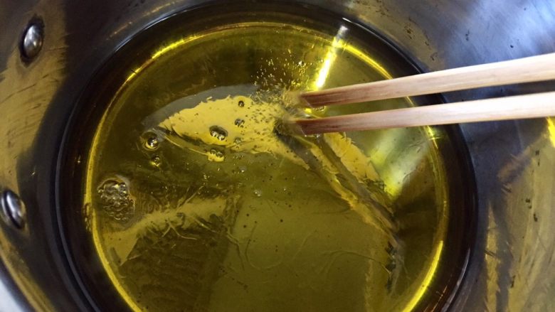 快手早餐---胡萝卜土豆饼,中火加热到筷子(竹筷子或者木筷子)放进去冒小泡为止,就可以放食物进去煎炸了