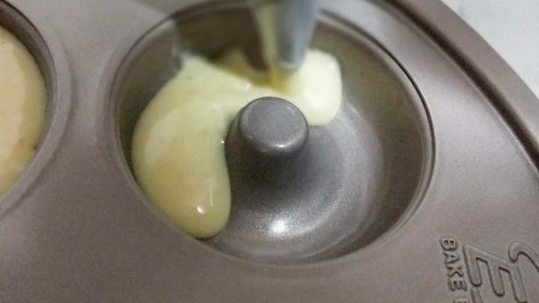 巧克力彩色糖珠甜甜圈,将做好的蛋糕糊装入裱花袋中,再挤入模具中即可。