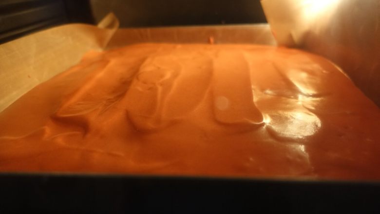 红丝绒波点蛋糕卷,取出烤好的波点,倒入红丝绒蛋糕糊,用管道抹平震泡。放入烤箱继续烤制18-20分钟。