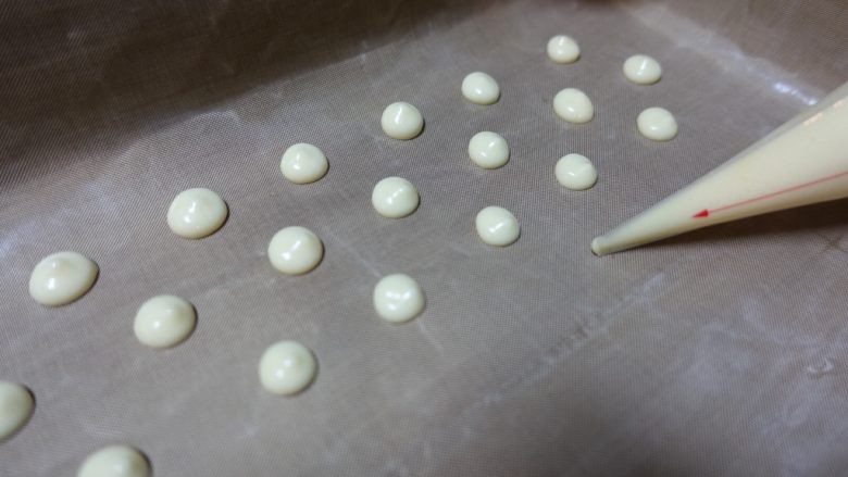 红丝绒波点蛋糕卷,舀一大勺混好的蛋糕糊到裱花袋里,在垫好油布的烤盘内挤上大小均匀排列有序的波点。