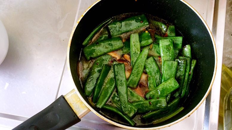 扁豆焖意面,继续翻炒均匀后，将泡干香菇的水倒入锅内，水量刚好与扁豆持平即可（若泡干香菇的水不够，可加入开水）。大火开始煮。