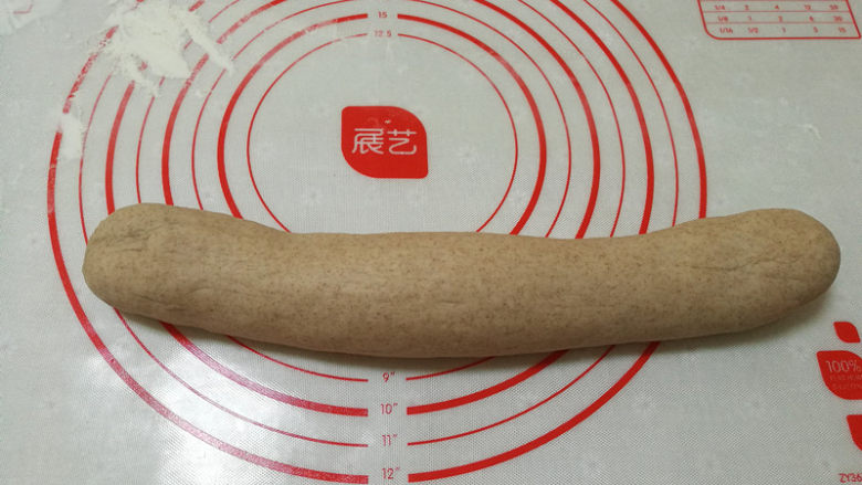 黑麦南瓜豆沙包,发酵好的面团放在案板上,排气,揉成长条。