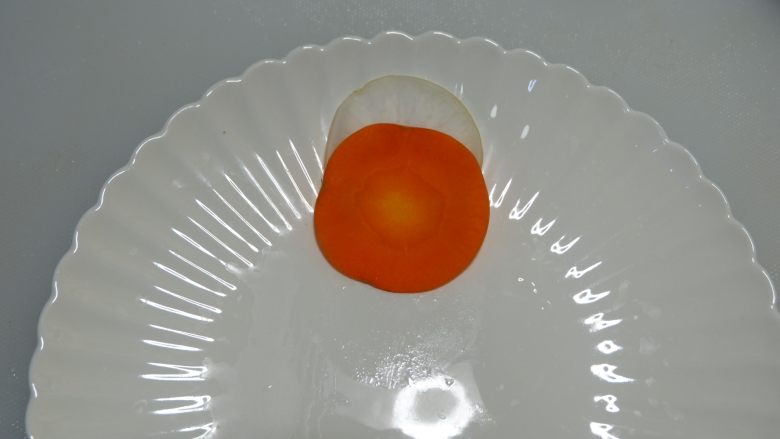 双萝开花喜迎春,取一片白萝卜,在取一片胡萝卜压在白萝卜上面