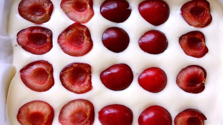 车厘子棉花蛋糕,倒入剩下的面糊，用刮刀刮平正，铺上第二层车厘子果肉，入烤箱150度烤50分钟，出炉倒扣，凉透撕掉油纸