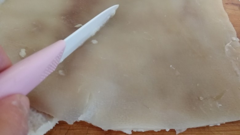 年菜_东北自制皮冻,焯好的猪皮用锋利的匕首刀刮猪毛。现在的猪皮一般都很干净,简单刮一下就行。