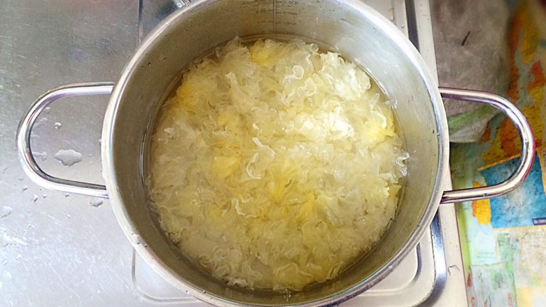 木瓜炖银耳,银耳泡好后,冲洗干净,去蒂摘成小碎片,倒入汤锅中。再倒入没过银耳的水,盖上盖子。大火烧开后,转小火煮大约25分钟。