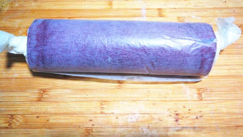 【情人节】红丝绒蛋糕卷,借助擀面杖用油纸把蛋糕卷卷起来,油纸两边收紧,定型1时。