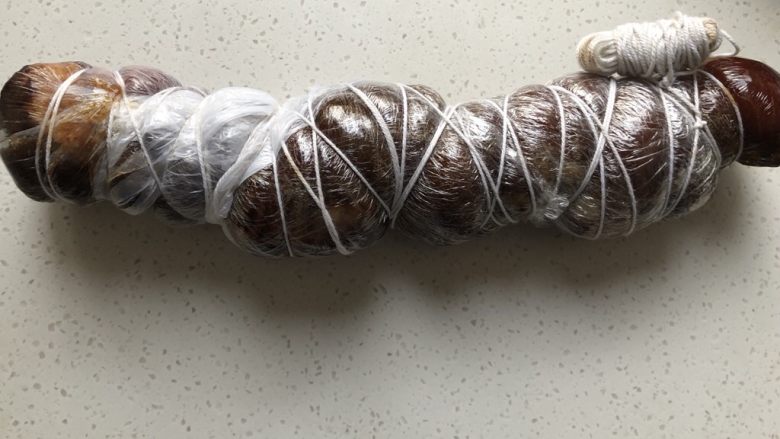秘制酱肘子,用保鲜膜将晾至温热的肘子横着用保鲜膜紧紧包裹起来,用线缠成木乃伊,越紧越好,晾凉放冰箱冷藏过夜