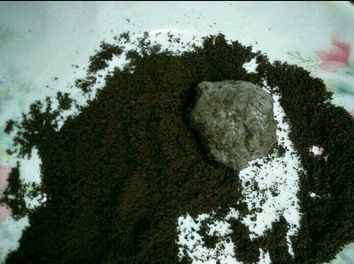 奥利奥樱花芝士蛋糕,将奥利奥芝士糊分成15克一份的量捏成圆型,放入余下的奥利奥碎中滚一圈,让奥利奥碎到沾在芝士团上。