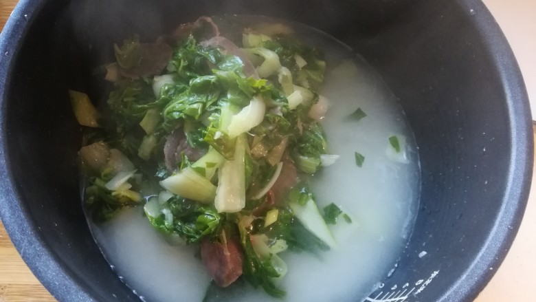 年味~腊肠青菜饭,把炒好的青菜腊肠倒在米上面。不用搅拌,因为米搅拌上来了以后容易夹生不熟。