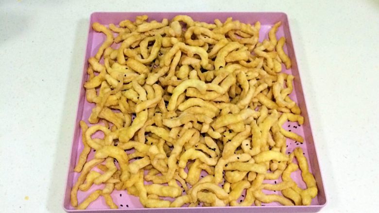 香酥沙琪玛,炸好的面条放入盘内,加入适量的黑芝麻。