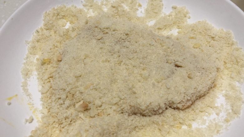 面包糠炸猪排,用手指压几下,帮助面包糠粘住,抖去过多的面包糠