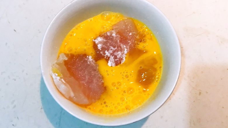 香煎黑椒龙利鱼,把腌制好的龙利鱼段放入鸡蛋液中,均匀的裹上一层蛋液