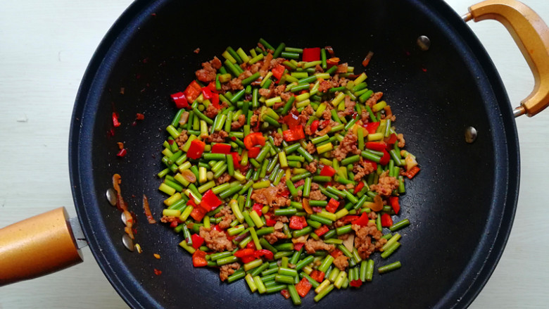 【肉末炒蒜苔】,下入红辣椒丁翻炒均匀,淋入<a style='color:red;display:inline-block;' href='/shicai/ 718'>料酒</a>,生抽,翻炒均匀