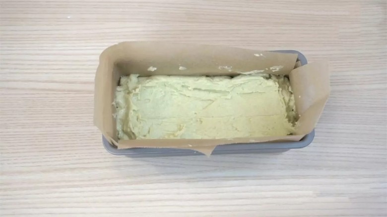 牛油果磅蛋糕,6寸磅蛋糕模具里铺上烘焙纸防粘(或在模具里先涂一层黄油,再撒上一层面粉,抖去多余的面粉,防粘),模具里倒入面糊,涂抹成中间凹,两头凸的形状。