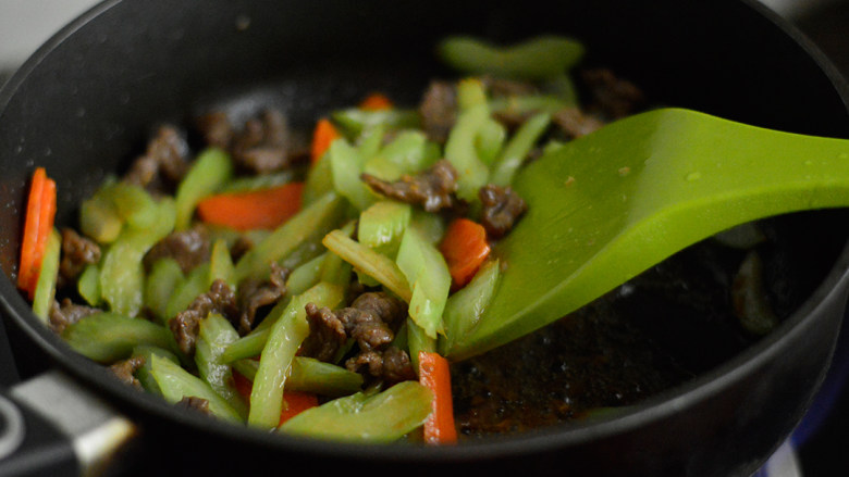 西芹炒牛肉,炒至断生后调入酱油,翻炒均与
