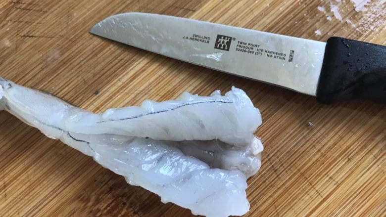 香酥黄金虾,再把虾身上的皮剥掉,留下虾尾那一节,然后从虾肚子那里用刀切开,切记不要把虾背也切开了,顺便把虾线从虾肚子切开的口拽出来。