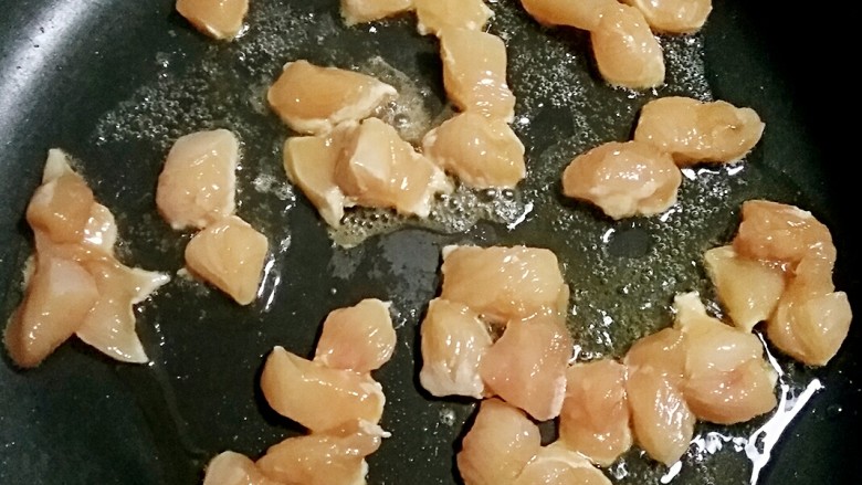 双椒鸡丁,锅中适量油烧至7分热,放入腌制好的鸡丁,翻炒。