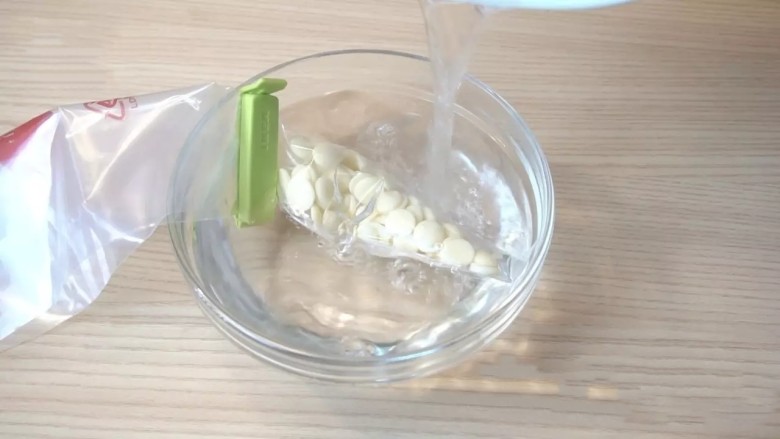 蓝莓芝士慕斯蛋糕,装饰:白巧克力装入耐高温的一次性裱花袋,倒入50-60度的热水(手可以触碰的温度),让白巧克力融化。