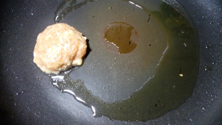 豆角焖肉饼,锅里放少许油,小火烧热后,用勺子取一勺肉馅,放在锅里煎。