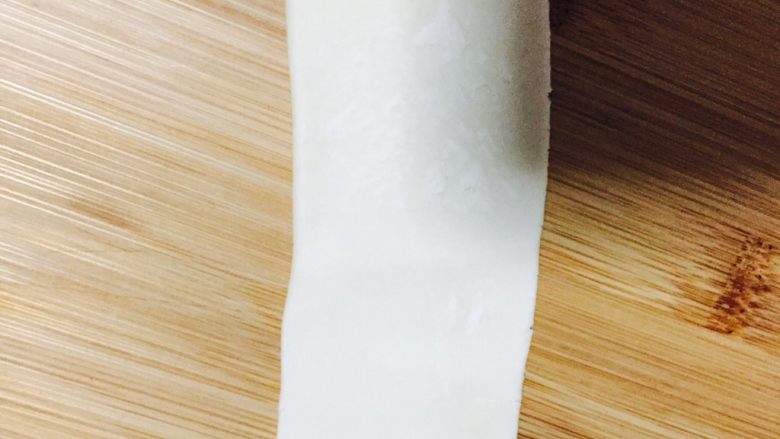 自制蛋黄酥,把卷好的面团,再次用擀面杖擀成长椭圆形面片