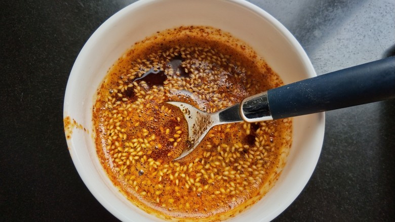自制饺子蘸料(附辣椒油的制作方法),烧至油微微冒烟,将油淋入碗中,用勺快速搅拌均匀,辣椒油就做好了(我是用汤勺把油分三次舀入碗中,辣椒粉发出滋滋的声音,这样红油就出来了)。