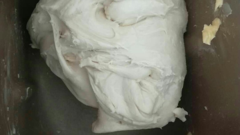 奶香糯米排包,加入黄油后,要观察搅拌桶,如果边沿有黄油可以用手处理下,把黄油放在面团上,继续和面。