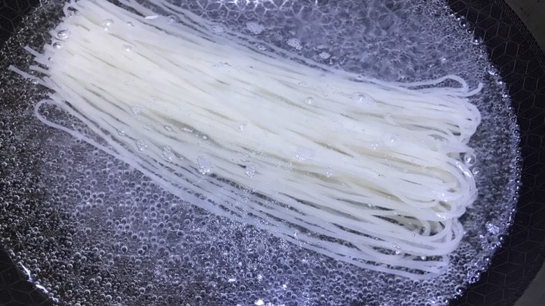 酸豆角肉丁米线,锅中放入矿泉水,直接将米线放入水中煮熟,水开后约10分钟即可;
