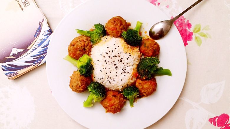 土豆牛肉丸子烩饭,装盘,先将盘子底部淋上茄汁,再扣碗米饭,摆上丸子和西兰花即可。红配绿,看着就满满的食欲!还可在米饭上撒少许炒熟的黑芝麻装饰。