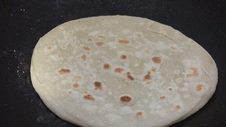 大年初四 烙大饼,然后盖上锅盖儿将饼的两面烙制浅浅的金黄色。烙饼时要不停的转动饼,让饼受热均匀。