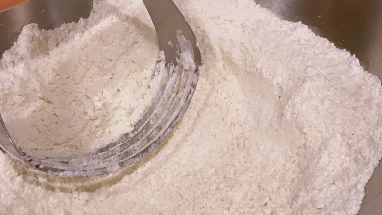 蜜红豆司康—星巴克版,用切拌器或刮板,不断地将奶油切开,跟面粉结合成小粒状。此步骤也可以直接用手,将黄油块跟面粉一起揉碎,但要注意别让手温将黄油融化开,这样会影响到成品的口感。