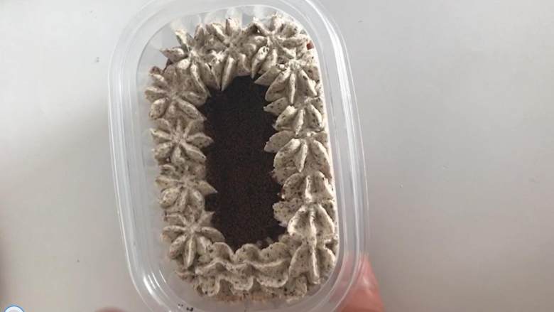 奥利奥咸奶油蛋糕盒子,最后挤上在表面外圈挤上一圈奥利奥奶油,中心处撒上奥利奥粉即可。