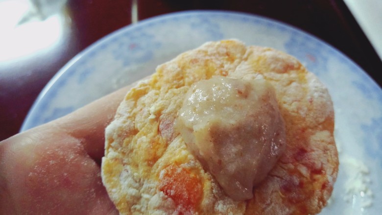 芋泥柿饼,将面团揪成小剂子,手心撒面粉,面团很软,轻轻按压摊在手上,粘了就撒些面粉,四周压扁一些,中间放一勺芋泥,包住