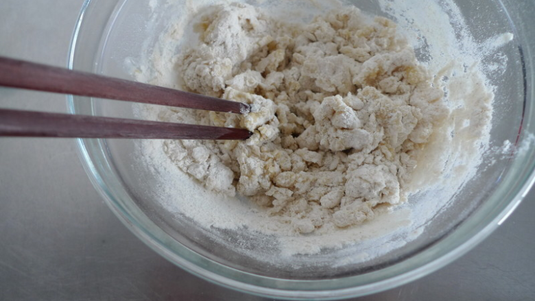 芝麻千层油酥火烧,一边加入滚烫的热水,一边用筷子搅拌。冷水的部份批次慢慢加入,建议保留1/3左右的冷水作为调整面团湿度用。