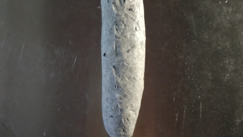 黑芝麻软欧包,从上至下卷起来,捏紧底边,底边朝下放在烤盘里。