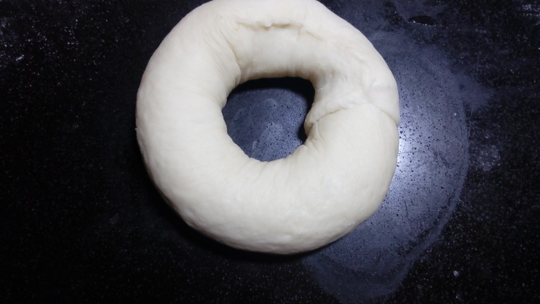 原味贝果(超详细版),剪五张比圆环稍大的油纸(因为等下煮的时候方便拿取,不会粘在烤盘上,而破坏了整好的形状。)把整型好的面团放在油纸上,再整理一下圆环的形状,保证中间孔洞不要太小。