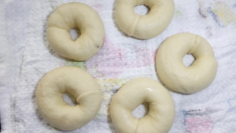 原味贝果(超详细版),一面煮30秒后,翻面再煮30秒。糖水温度不要太高,如果水温高就应当减少煮面时间,糖水在半开时的温度最合适。这样煮好后的面团也是表面也是基本光滑的。