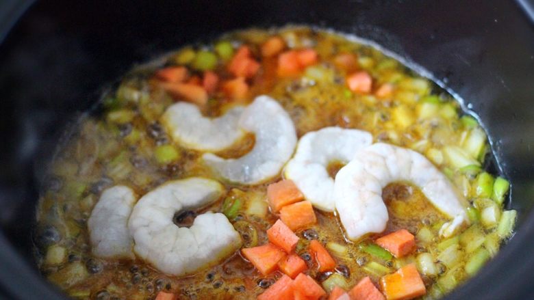 什锦咖喱虾仁蛋炒饭(砂锅版),加入洗净的虾仁和胡萝卜丁后、小火继续翻炒片刻